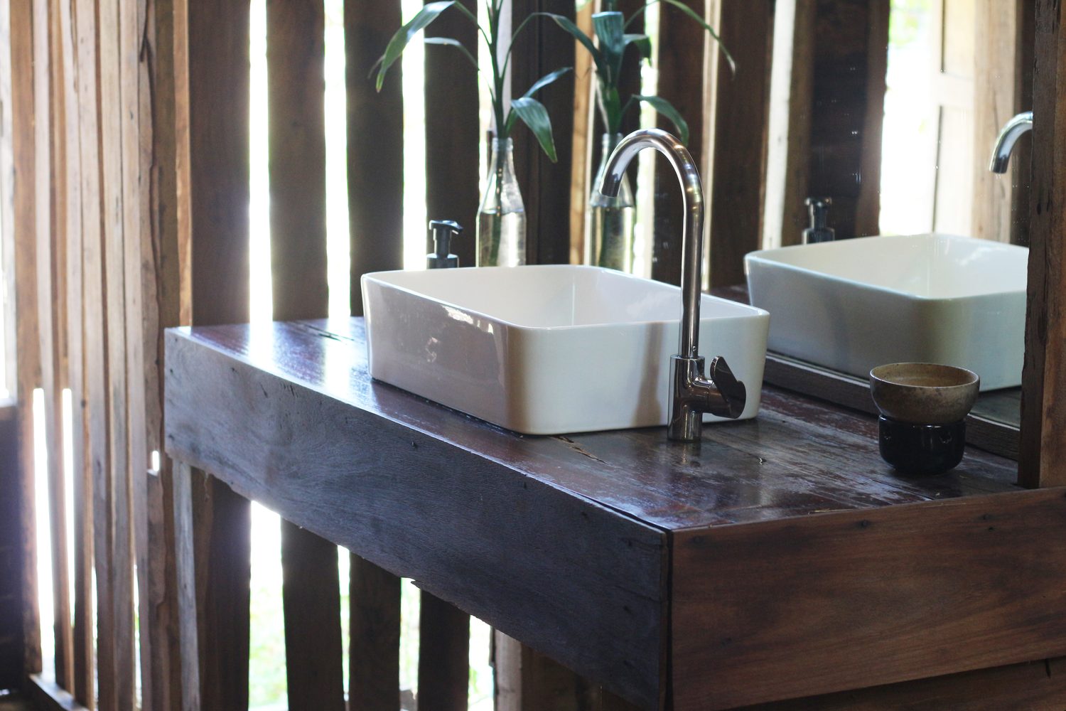 Vasque à poser blanche installée sur un meuble en bois dans une salle de bain moderne.